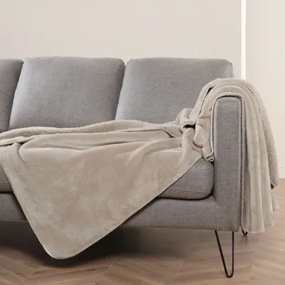 A beige blanket draped over a gray sofa.