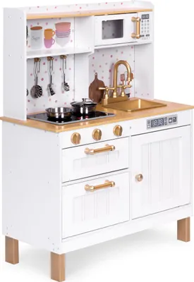 A white wooden toy kitchen with gold accents, featuring a stovetop, sink, microwave, and storage cabinets.
