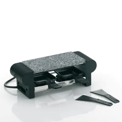 A raclette grill with a granite stone top and two small pans, along with two spatulas, is displayed against a white background.