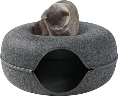 A gray cat sits in a gray donut-shaped cat bed with an opening in the front.