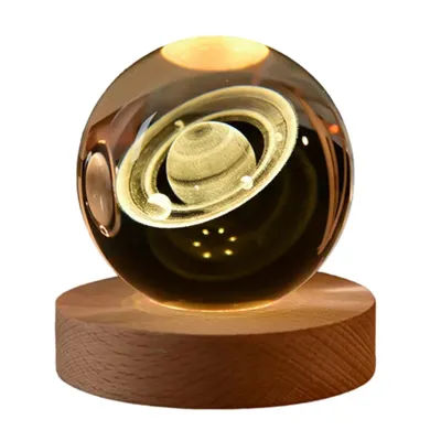 A crystal ball with a 3D engraved image of Saturn and its rings, illuminated from below by a wooden base with an LED light.
