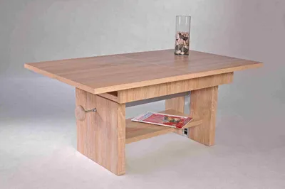 A light wood coffee table with a shelf underneath and a vase of stones on top.