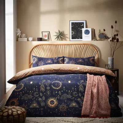 A bedroom scene with a bed dressed in celestial-themed bedding.