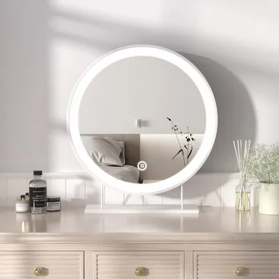 A round vanity mirror with LED lighting is placed on a wooden dresser.