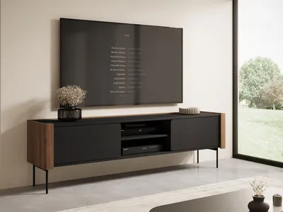A modern TV lowboard with a television mounted above it, in a well-lit room with a large window showing an outdoor scene.