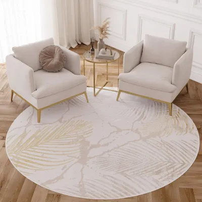 Two cream armchairs are placed on a round rug with a palm leaf pattern in a living room setting.