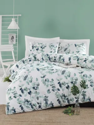 A bedroom scene with a bed dressed in green leaf-patterned bedding against a light green wall.