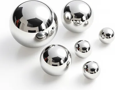 Several polished metal spheres of varying sizes are arranged on a white surface.