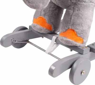 Close-up view of the feet and base of a stuffed elephant toy on a rocking mechanism.