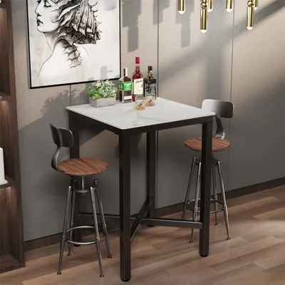 A bar table with two stools in a modern setting, with bottles of alcohol and a plant on the table.