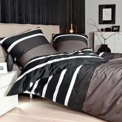 A neatly made bed with striped bedding in a modern bedroom setting.
