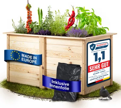 A wooden raised garden bed filled with various plants, including tomatoes, peppers, herbs, and lavender. It is placed on artificial grass with a black plastic liner bag next to it. There are promotional labels on the side of the bed.