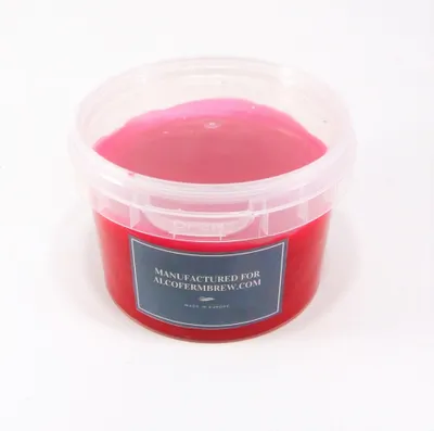 A plastic tub filled with red wax, with a label on the front.