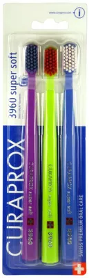 A pack of three Curaprox toothbrushes in purple, green, and blue.