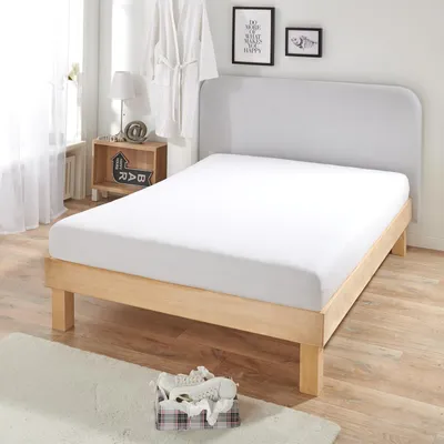 A white fitted sheet on a wooden bed frame in a bedroom setting.