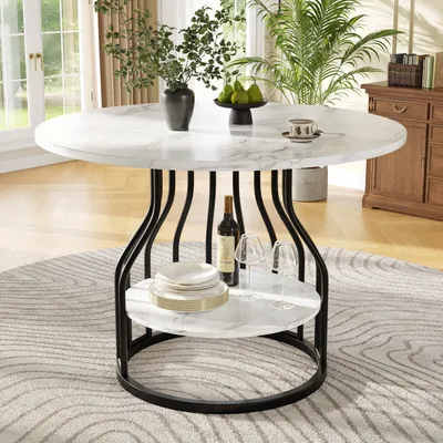 A round dining table with a marble-like top and black metal legs, set in a dining room with plants and furniture in the background.