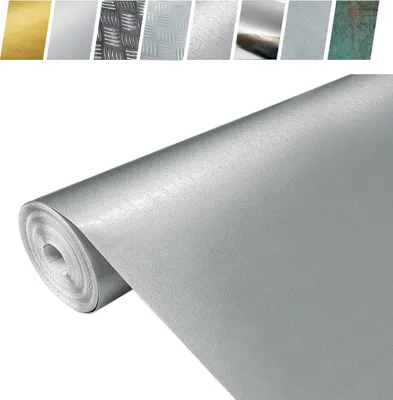 A roll of metallic wallpaper or material with a brushed silver finish, with smaller samples of different metallic finishes visible in the background.