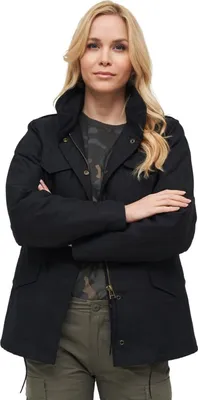 A woman wearing a black jacket and green pants, posing with her arms crossed.