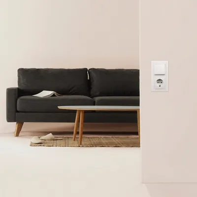 A minimalist living room scene with a dark gray sofa, a coffee table, and a light pink wall.