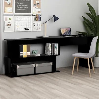 A modern black desk with a laptop, lamp, and storage boxes, set against a gray wall with organizational boards.