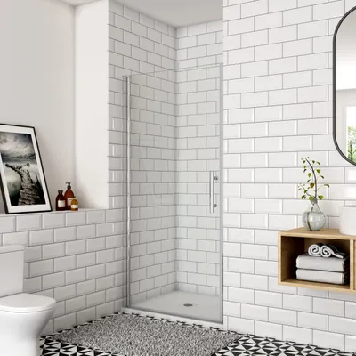 A modern bathroom with white subway tiles, a glass shower door, a toilet, and a shelf with decorative items.
