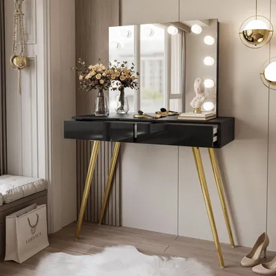 A black vanity table with gold legs, a lighted mirror, and decorative items in a room setting.