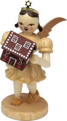 Ein hölzerner Engel mit Flügeln hält ein Lebkuchenhaus in den Händen und steht auf einem runden Sockel
