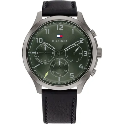 A close-up, front-facing studio shot of a Tommy Hilfiger men's watch with a green dial and black leather strap.