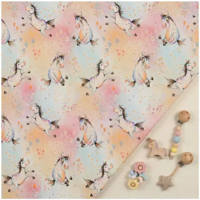 Hauptansicht Swafing Nils Baumwolljersey mit Einhorn-Motiv in Pastellfarben, dekoriert mit Baby-Accessoires, hochwertige Meterware für Kinderbekleidung.