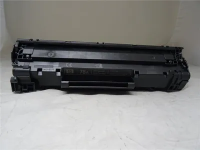 A black toner cartridge is shown on a light gray surface.