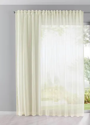 A cream-colored curtain hanging in front of a window.