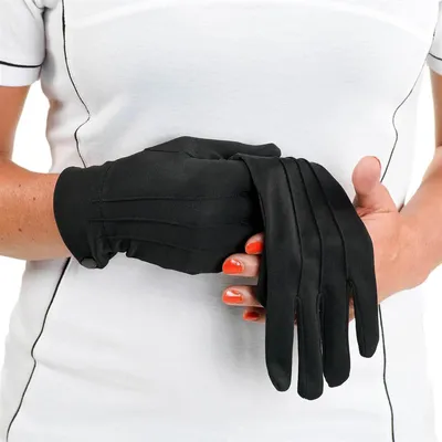 A person wearing a white shirt is putting on black gloves.