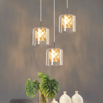 A set of three pendant lights hanging above a table with plants and vases.