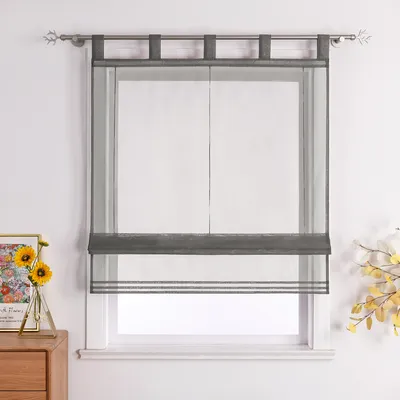 A sheer gray Roman blind with decorative stripes hangs in a window.