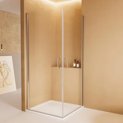 A modern bathroom corner shower enclosure with glass doors and silver frames, set against a beige wall.