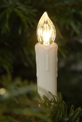 A close-up of a white LED candle light with a flame-shaped bulb, attached to a Christmas tree.