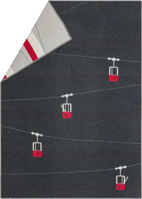 A dark gray blanket with a pattern of gondolas on cables. The top left corner shows a folded section of the blanket with a striped pattern.