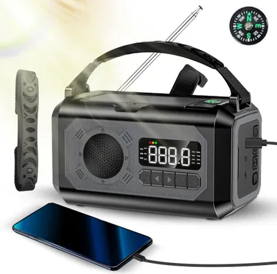 A black and gray emergency radio with a compass and a smartphone charging next to it, with light rays in the background.