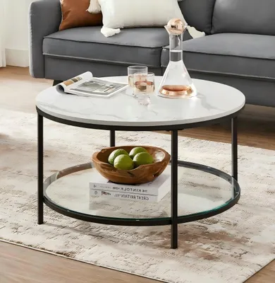 A round coffee table with a marble-like top and a glass shelf is placed in a living room setting.