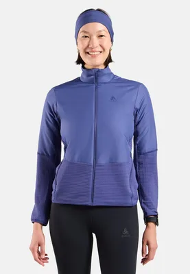 Frau trägt eine blaue Odlo Essentials Insulator Hybrid-Laufjacke mit Reißverschluss und ein passendes Stirnband