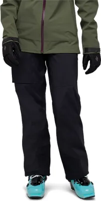 Damen Hardshellhose "Recon Stretch LT Pants" von Black Diamond; schwarz; kombiniert mit einer grünen Jacke und blauen Skischuhen.