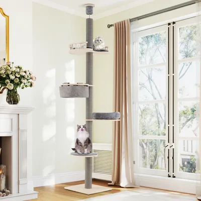 A cat tree is set up in a living room next to a window and a fireplace.