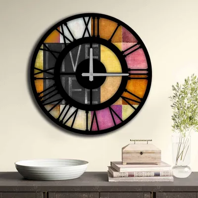 A colorful wall clock with Roman numerals is displayed on a wall above a dark wooden cabinet. A white bowl and a stack of books with a wooden box are on the cabinet.