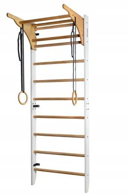 A white and wooden indoor climbing frame with gymnastic rings hanging from it.