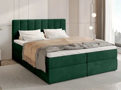 A green upholstered bed with white bedding and a beige throw blanket is shown in a bedroom setting.