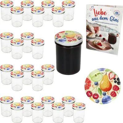 A collection of glass jars with decorative lids, a jar filled with dark jam, a recipe book, and a decorative plate, all arranged on a white background.