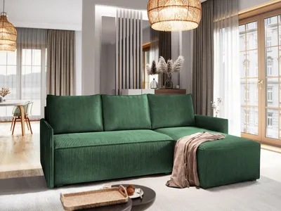 A modern living room with a green sectional sofa and an ottoman, featuring a woven pendant light and large windows.