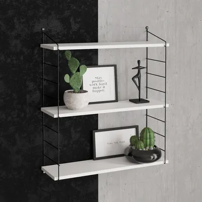 A white three-tiered shelf unit with decorative items on a wall split between black and gray concrete textures.