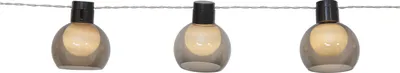 A string of three solar-powered lights with smoky gray glass shades and black caps, suspended on a thin wire against a white background.