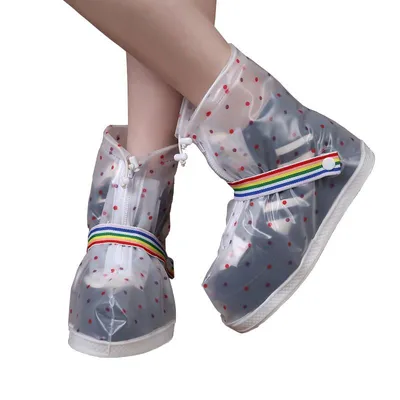 A pair of transparent rain boots with red polka dots worn by a person, shown from the front.